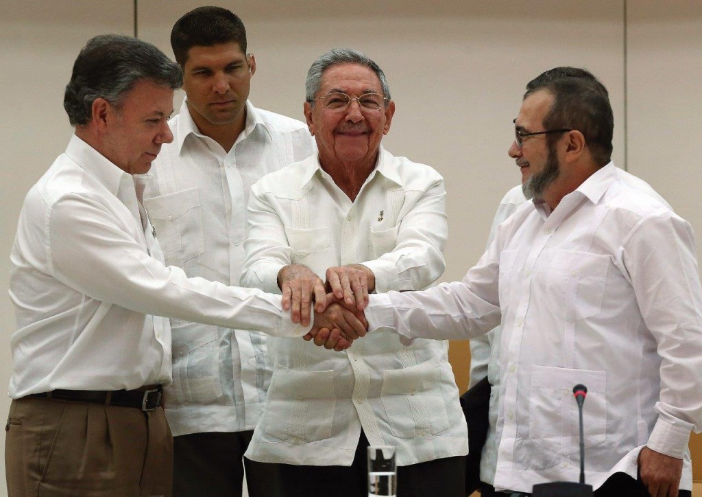 O ditador Raúl Castro junta as mãos do presidente da Colômbia Juan Manuel Santos (esq.) e do chefe guerrilheiro “Timochenko” (dir.) em Havana
