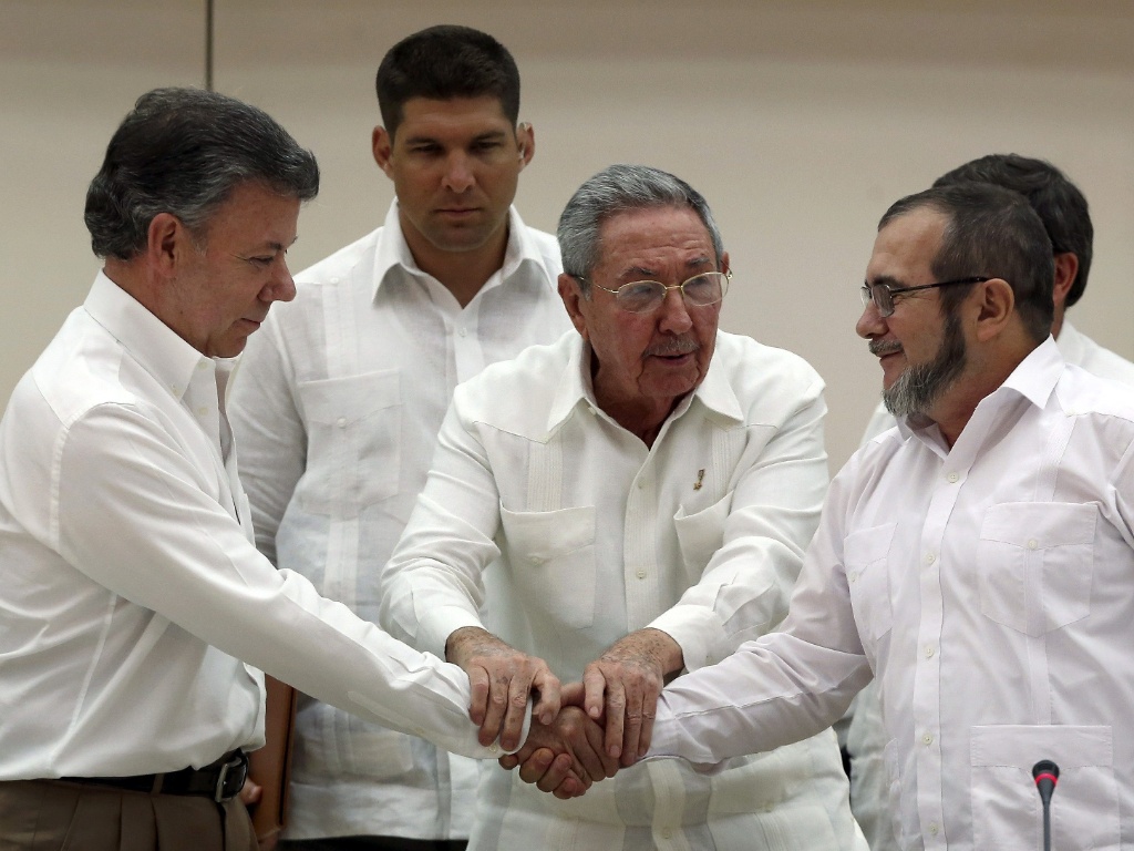 À esq., Santos, o presidente colombiano, aperta a mão do líder terrorista das FARC, Rodrigo Londono, no anunciado “acordo de paz” selado pelo ditador cubano Castro (no centro)