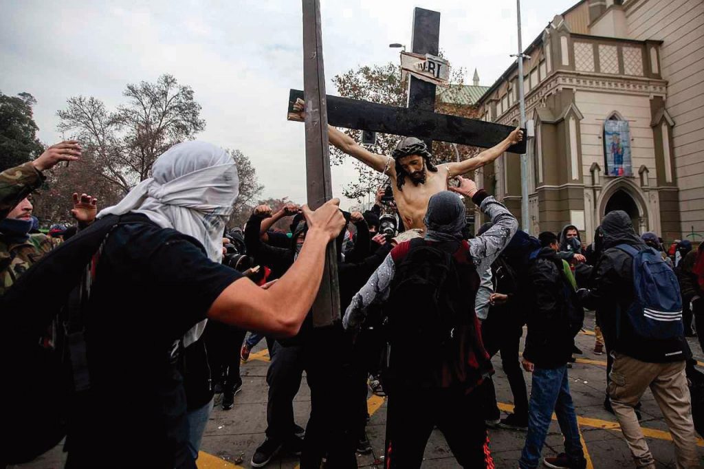 Violenta manifestação esquerdista profana igreja no centro de Santiago do Chile e retira de seu interior, sem nenhuma reação dos presentes, um antigo Crucifixo, que é brutal e sacrilegamente golpeado, atirado ao chão e quebrado.